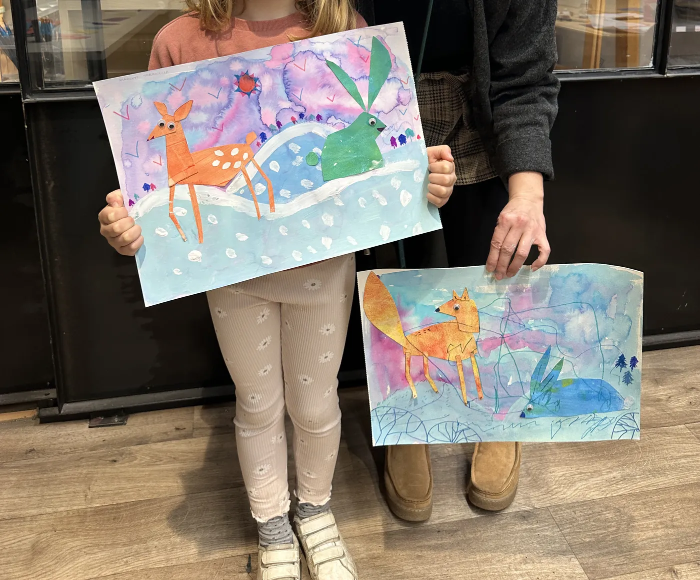 Deux enfants présentent leurs collages sur le thème de l'hiver