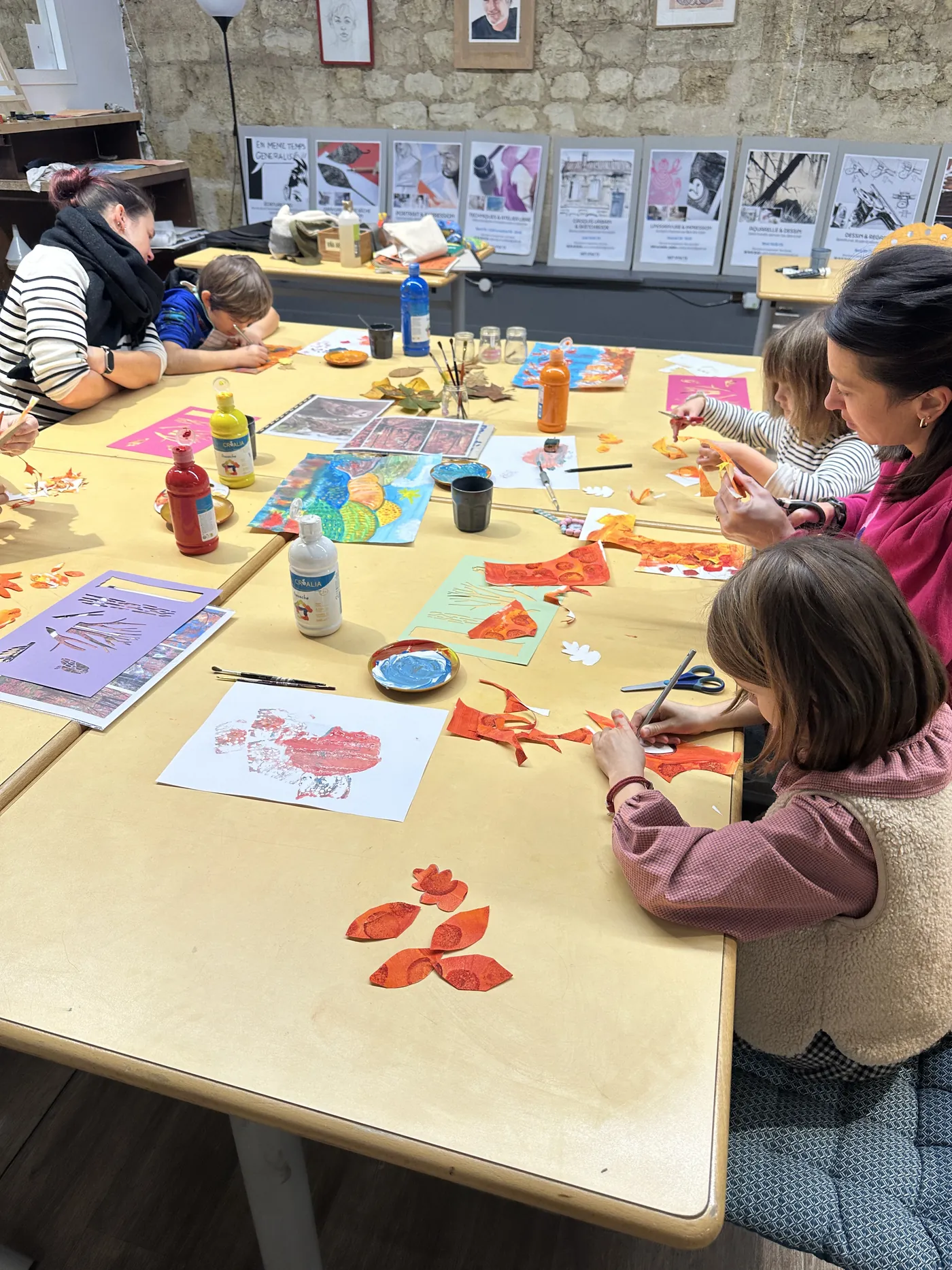Parents et enfants découpent et collent autour de la table
