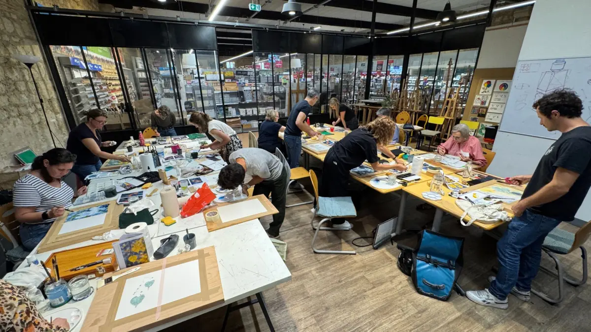 Une séance aux Ateliers de la Verrière : les participants peignent à l'aquarelle autour des grandes tables, dans le magasin Boesner